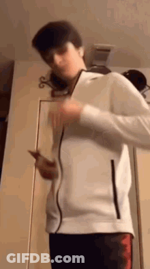 Young Man In White Jacket Holding Phone GIF