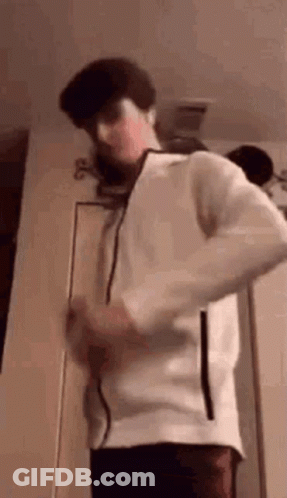 Young Man In White Jacket Standing In Front Of Door GIF