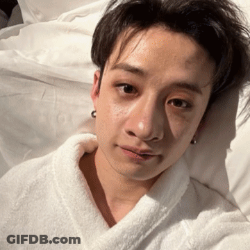 Young Man In White Robe Lying In Bed GIF