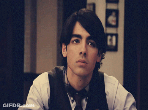 Young Man In White Shirt And Brown Vest GIF