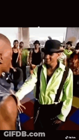 Young Man In White Shirt And Brown Vest Looking At Camera GIF