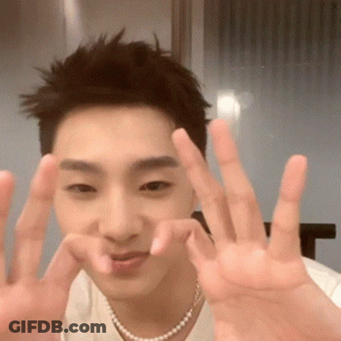 Young Man In White Shirt And Pearl Necklace Making Peace Sign GIF