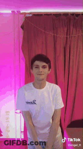 Young Man In White Shirt In Front Of Pink Curtain With TikTok GIF