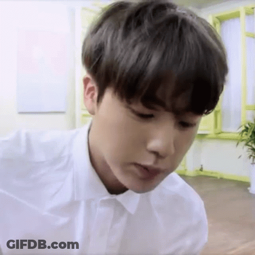 Young Man In White Shirt Sitting In Room With Plant GIF
