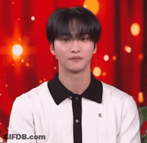 Young Man In White Shirt With Black Collar In Front Of Red Curtain GIF