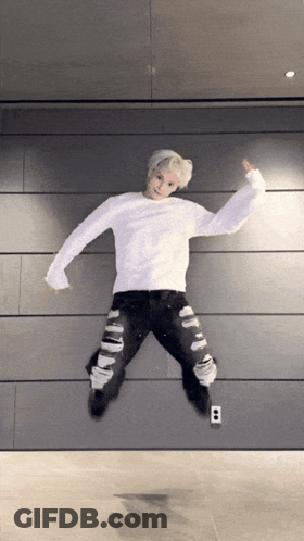 Young Man In White Sweater Jumping In Ripped Jeans GIF
