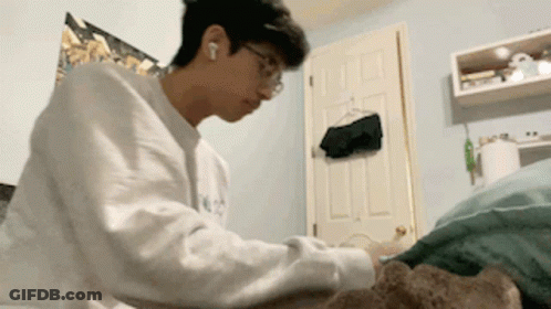 Young Man In White Sweater Laying On Bed GIF