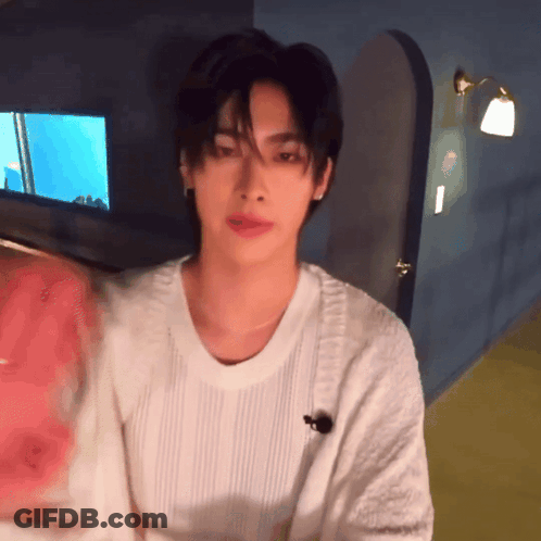 Young Man In White Sweater Standing In Room GIF