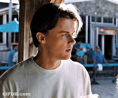 Young Man In White T-Shirt Holding Paper In Front Of Building GIF