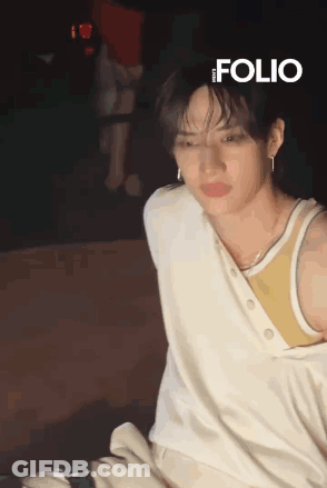 Young Man In White Tank Top And Earrings Sitting GIF