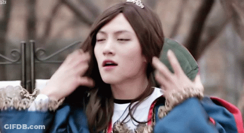 Young Man In Wig And Crown Holding Green Bag GIF