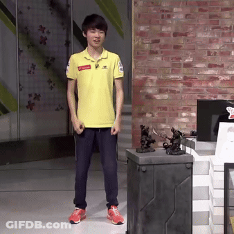 Young Man In Yellow Shirt In Front Of Brick Wall And Toy Display GIF
