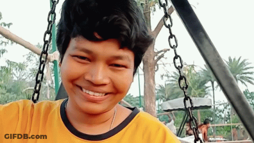 Young Man In Yellow Shirt Smiling On Swing GIF