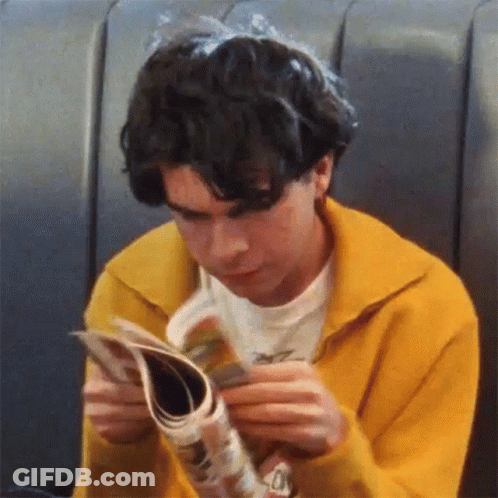 Young Man In Yellow Sweater Reading Magazine GIF