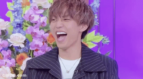 Young Man Laughing In Front Of Flowers GIF