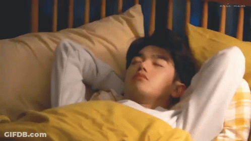 Young Man Laying In Bed With Yellow Comforter GIF