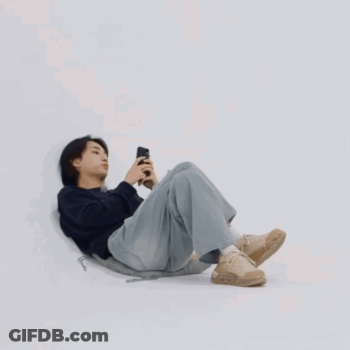 Young Man Laying On Floor Looking At Phone GIF