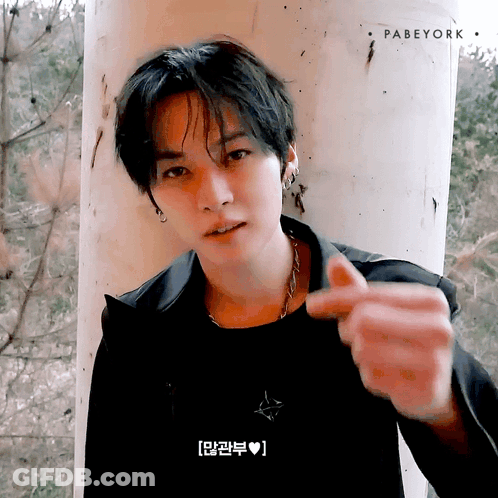 Young Man Leaning Against Pillar Making Heart With Fingers GIF