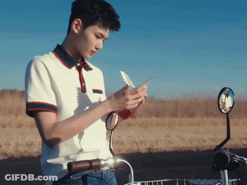 Young Man Looking At Phone Next To Bicycle GIF