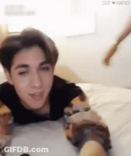 Young Man Lying On Bed Arms Outstretched GIF