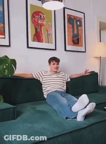 Young Man Lying On Green Couch Arms Outstretched GIF