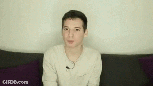 Young Man On Couch Making Funny Face Hands Up GIF