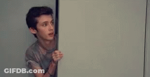 Young Man Peeking From Door Holding White Board GIF