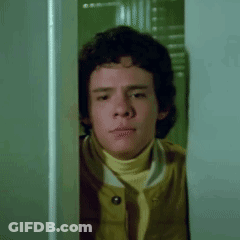 Young Man Peeking Out Of Doorway GIF