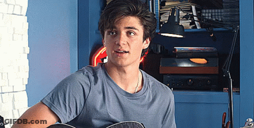 Young Man Playing Guitar In Room With Lamp GIF