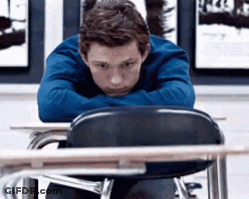 Young Man Resting Head On Arms At Desk GIF