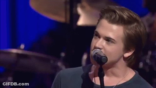 Young Man Singing Into Microphone On Stage GIF