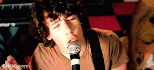 Young Man Singing Into Microphone Playing Guitar GIF