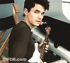Young Man Sitting In Chair Holding Guitar GIF