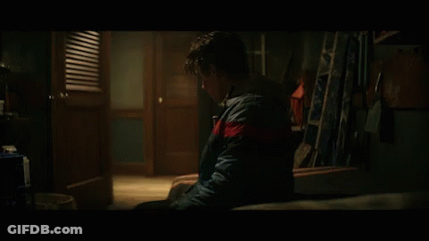 Young Man Sitting In Dark Room With Ladder GIF