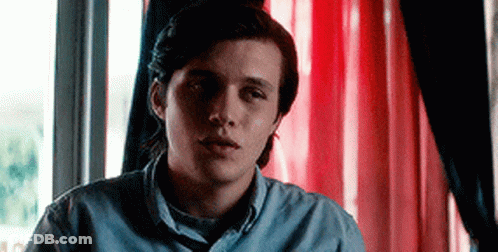Young Man Sitting In Front Of Red Curtain Window GIF
