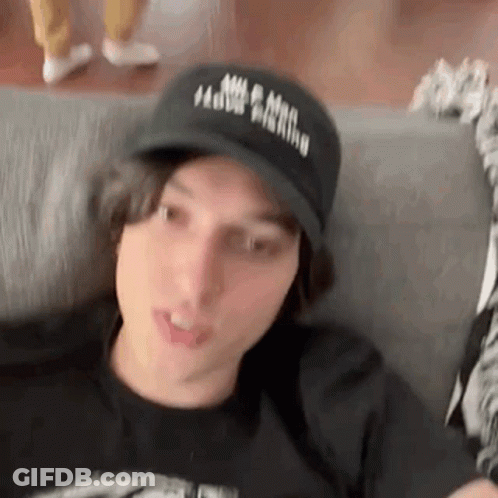 Young Man Sitting On Couch In Black Hat GIF