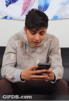 Young Man Sitting On Couch Looking At Phone GIF