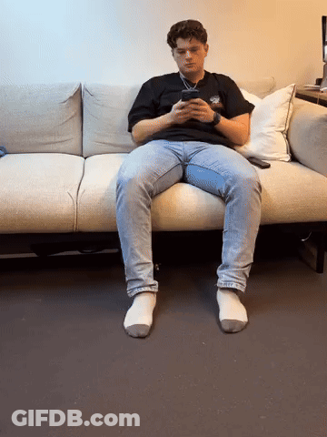 Young Man Sitting On Couch Looking At Phone GIF