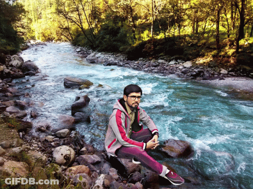 Young Man Sitting On Rock By River GIF