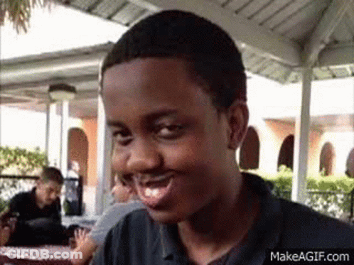 Young Man Smiling And Making Funny Face At Table GIF
