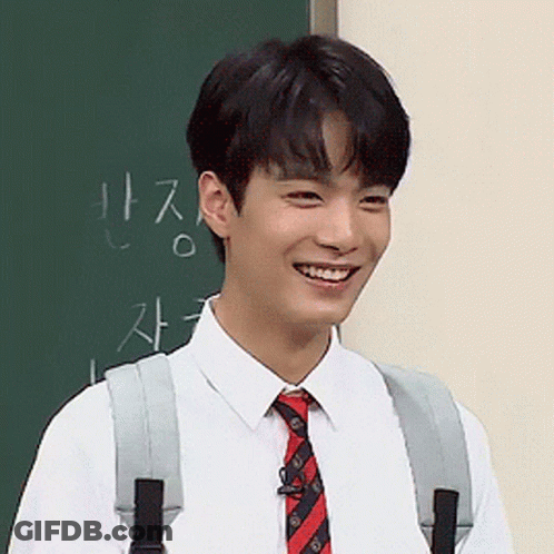 Young Man Smiling At Blackboard With Chinese Writing GIF