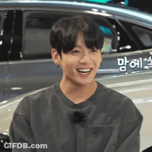 Young Man Smiling By Car With Foreign Writing GIF