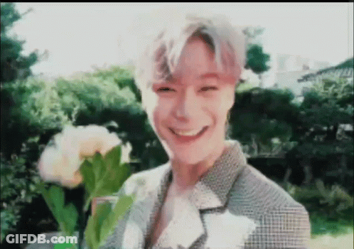 Young Man Smiling Holding Flowers GIF