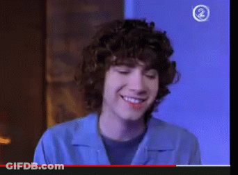 Young Man Smiling In Front Of Blue Wall With Number 2 GIF