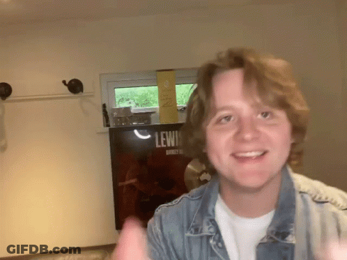 Young Man Smiling In Front Of Lewis Sign GIF
