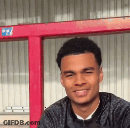 Young Man Smiling In Front Of Red Railing GIF