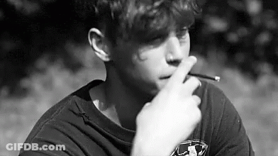 Young Man Smoking Cigarette In Park GIF