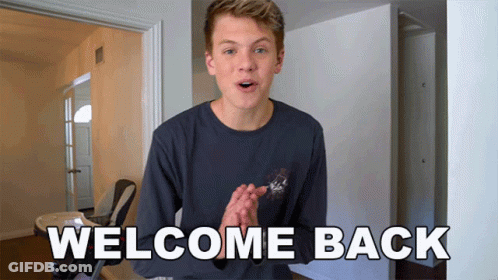 Young Man Standing Before Welcome Back Sign GIF