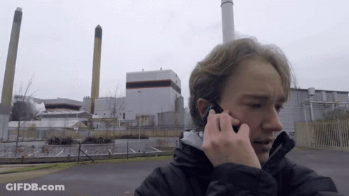 Young Man Talking On Cell Phone In Front Of Factory GIF