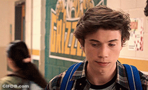 Young Man With Blue Backpack Walking Down Hallway GIF